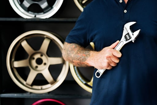 5 Reasons Why Your Garage Needs a Management System; a mechanic holding a wrench