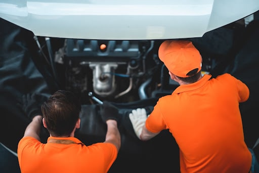 5 Reasons Why Your Garage Needs a Management System; two men working on an engine