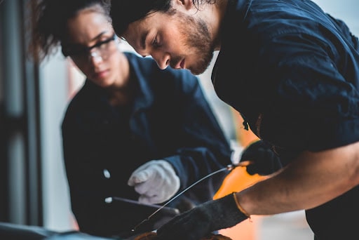 5 Reasons Why Your Garage Needs a Management System; two mechanics checking the oil levels of a car