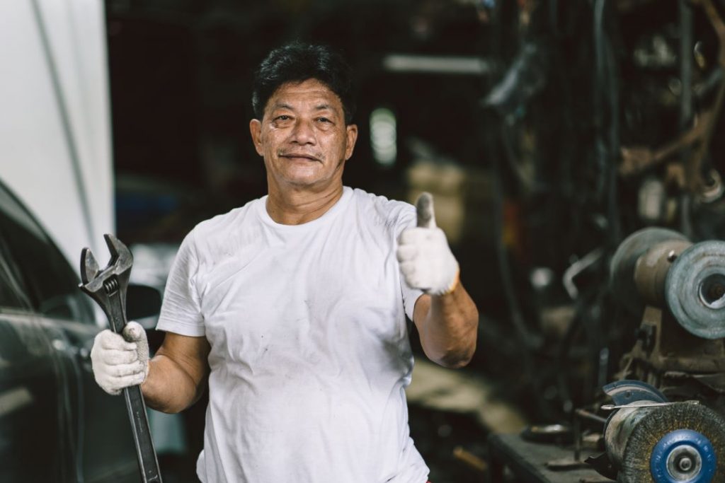 boost employee productivity, a car technician posing with a thumbs-up