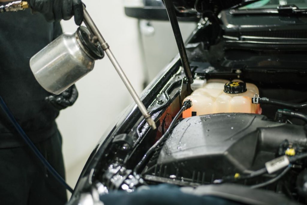 winter car care, a car technician injecting cleaning fluid in the engine
