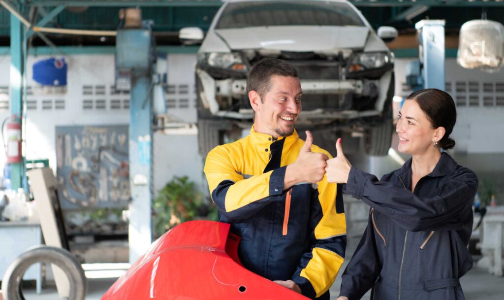 communicate with customers, a man and a woman showing each other a thumbs up sign with acar in the back