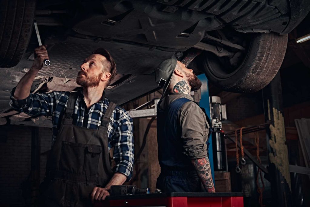 communication techniques, two auto repair technicians working on an overhead car