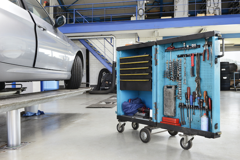 Garage equipment, elevated car near rack of equipment.