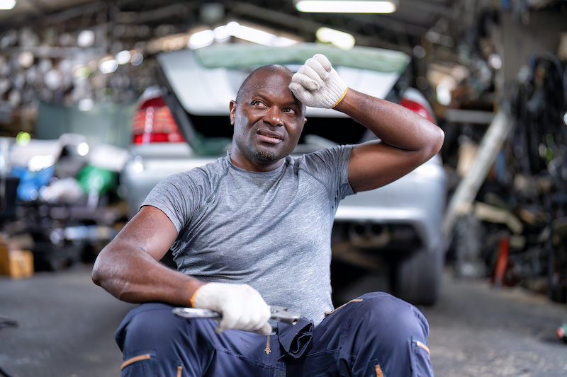 Sustainable garage, car repair mechanic sitting in garage.