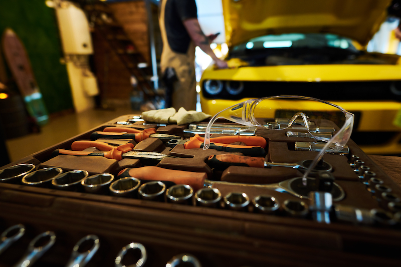 Garage equipment, mechanic fixing car near repair tools.