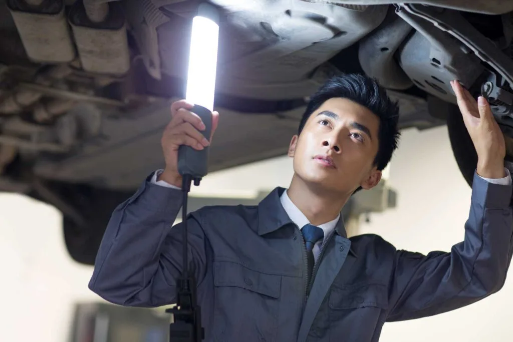 how to upgrade your garage, mechanic holding hand light against base of car